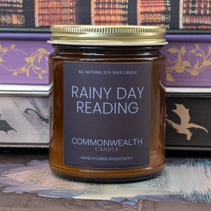 Candle jar labeled 'Rainy Day Reading' by Commonwealth Candle on a decorative background with books.