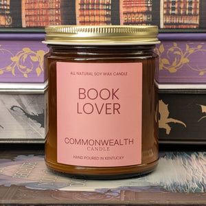 Candle jar labeled 'Book Lover' by Commonwealth Candle on a decorative background with bookshelf design.