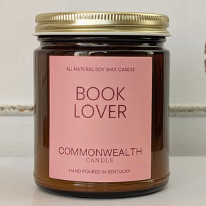 Candle in a glass jar with a pink label reading 'Book Lover' by Commonwealth Candle.