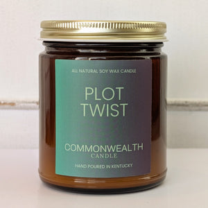 Candle jar labeled 'Plot Twist' by Commonwealth Candle on a light background