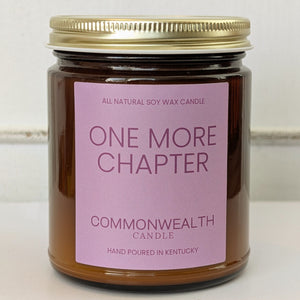 Candle jar with a pink label reading 'One More Chapter' by Commonwealth Candle on a white background.